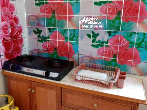 a counter with red roses on a wall at Honey Holiday Penthouse in Tanah Rata