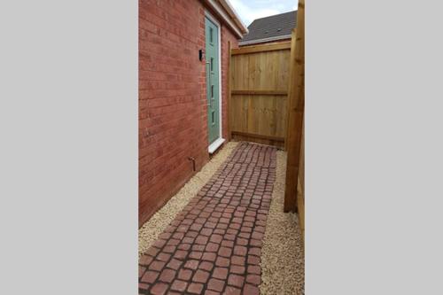 una pasarela de ladrillo que conduce a una casa con una valla de madera en Annex in Chippenham with Parking and WIFI, en Chippenham