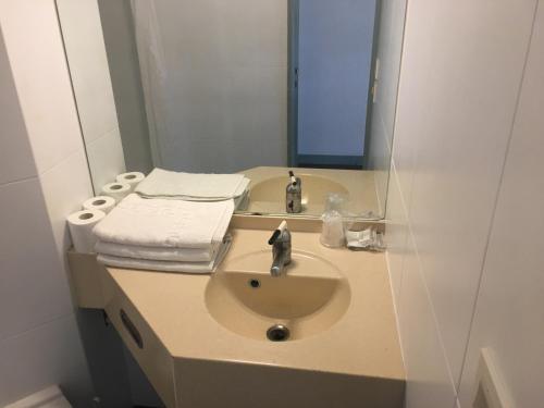 een badkamer met een wastafel en een spiegel bij Hôtel Motelia in Moissy-Cramayel