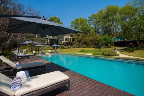 uma piscina com guarda-sol e cadeiras ao lado em Vivari Hotel and Spa by Mantis em Joanesburgo