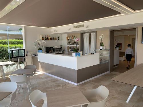 a woman walking into a restaurant with a counter and chairs at Hotel Stele di Nora in Pula