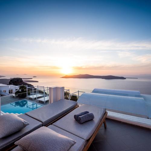 a villa with a swimming pool and the sunset at Andromeda Villas & Spa Resort in Imerovigli