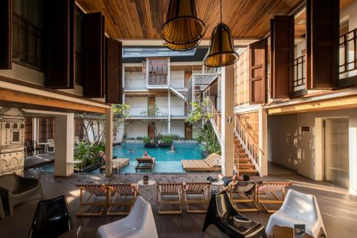 an indoor pool in a building with chairs and a table at Nanda Heritage Hotel in Bangkok