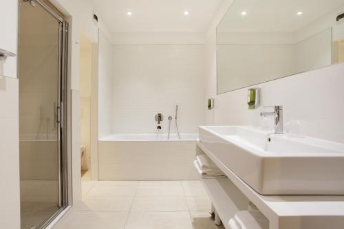 a white bathroom with a sink and a shower at Hôtel Rotonde in Aix-en-Provence