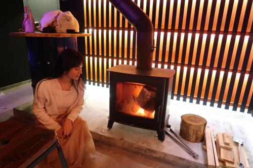 a woman sitting in front of a stove at B&B MIKAWA 2 - Kanazawa Fish Harbour in Kanazawa