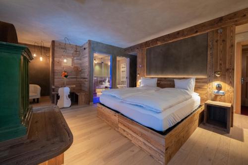 a bedroom with a large bed with a wooden headboard at La Roccia Wellness Hotel in Cavalese