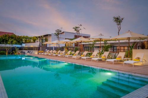 a large swimming pool with chairs and umbrellas at The Aviary Hotel in Siem Reap