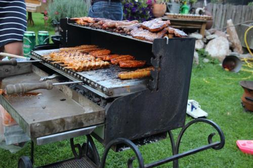 a grill with sausages and other food on it at Sachserhof Ferienwohnungen in Sachsenburg in Sachsenburg
