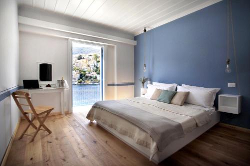 Dormitorio azul con cama, escritorio y ventana en Limani Life en Symi