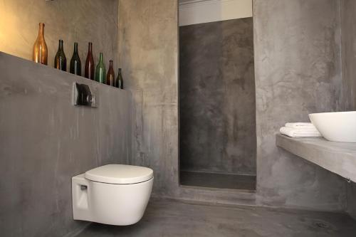 a bathroom with a toilet and a shelf with wine bottles at Limani Life in Symi