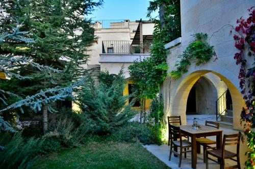 un patio con mesa y sillas en un jardín en Cappadocia Estates Hotel, en Mustafapaşa