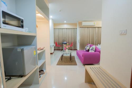 a living room with a pink chair and a table at Taragrand Donmuang Airport Hotel in Thanyaburi