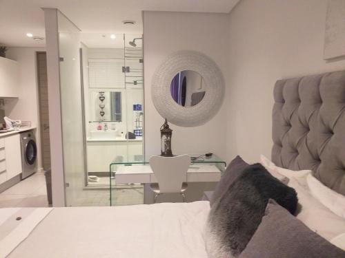 a bedroom with a bed and a desk and a mirror at No 2 Heleza Blvd Sibaya, Oceandune, Umhlanga Durban in Umdloti