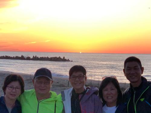 a group of people standing on the beach at sunset at B&B MIKAWA 2 - Kanazawa Fish Harbour in Kanazawa