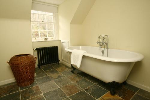 baño con bañera blanca y ventana en Find Me Out Holiday Cottage, en Dalmellington