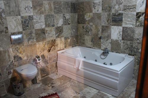 a bathroom with a tub and a toilet at Dilek Tepesi Cave Hotel in Ayvalı