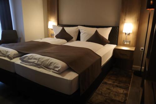a bedroom with a large bed with white sheets and pillows at Hotel Bispinger Hof in Bispingen
