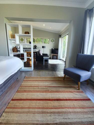 ein Schlafzimmer mit einem Bett und einem Stuhl sowie ein Wohnzimmer in der Unterkunft Lind End Guest Farm in Haenertsburg