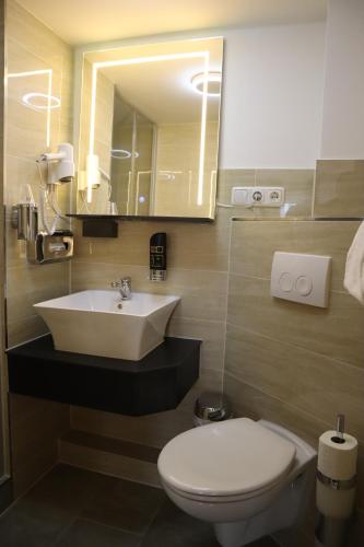 a bathroom with a sink and a toilet and a mirror at Hotel Bispinger Hof in Bispingen