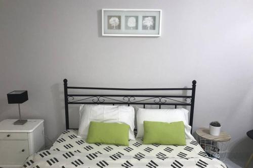 una camera da letto con un letto bianco e nero con due cuscini verdi di Istos Apartment 1 a Salonicco