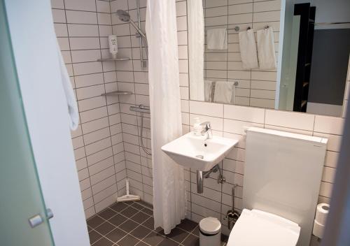 a bathroom with a sink and a toilet and a mirror at Pharmakon Hotel & Conferencecenter in Hillerød