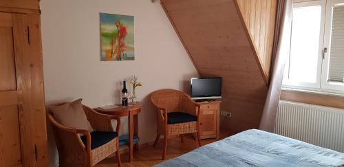 a bedroom with a small table with two chairs and a television at Weingut Schunck in Leinsweiler