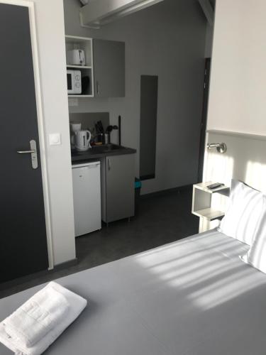 a bedroom with a white bed and a kitchen at Smart Appart Caen République in Caen