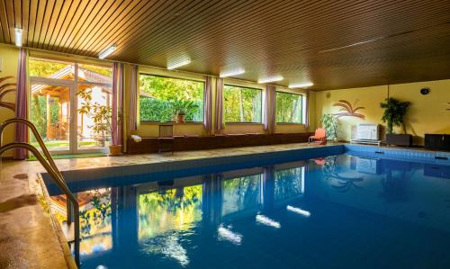 a large swimming pool in a house with windows at Landhotel Klingerhof in Hösbach