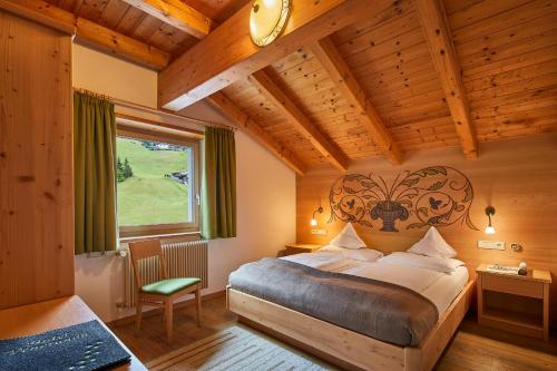 a bedroom with a large bed in a room with wooden ceilings at Hotel Pensione Veneranda in Corvara in Badia