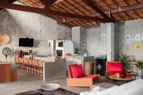 a living room with a kitchen with red chairs at Casa da Massagueira-AL in Marechal Deodoro
