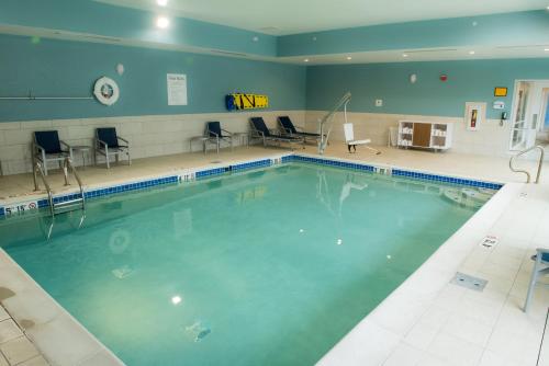a swimming pool in a gym with chairs and tables at Holiday Inn Express & Suites - Orland Park Mokena by IHG in Mokena