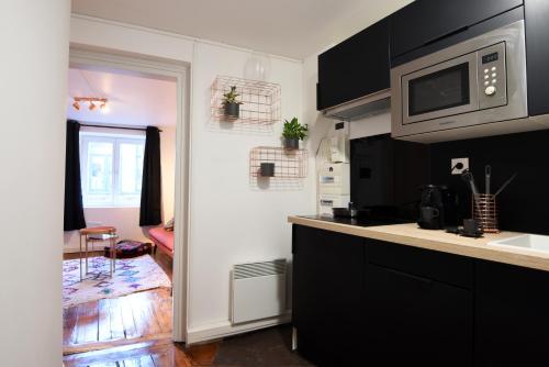 une cuisine avec des armoires noires et un four micro-ondes dans l'établissement NOCNOC - Le Cosy, Grand Place, à Lille