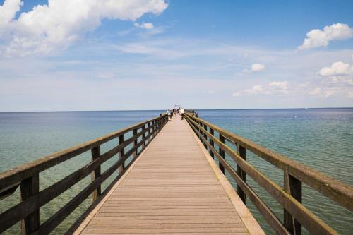 een houten pier strekt zich uit over het water bij Residenz Duene III in Boltenhagen