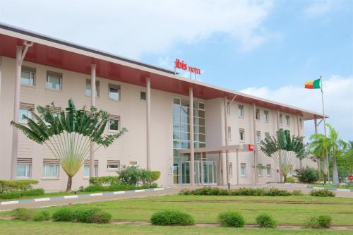 an exterior view of a hotel with a flag at Ibis Cotonou in Cotonou
