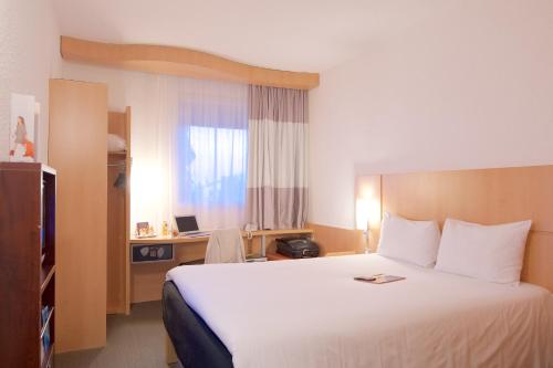 a hotel room with a large bed and a window at Ibis Cotonou in Cotonou