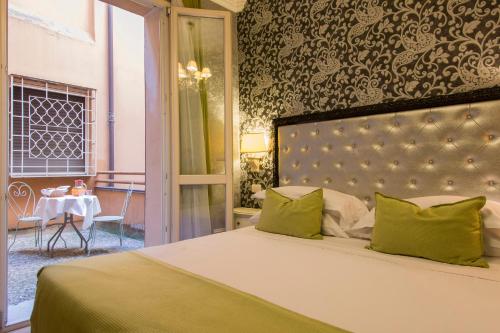 a bedroom with a bed with green pillows and a table at Hotel Pedrini in Bologna