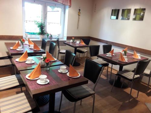- un restaurant avec des tables et des chaises avec des serviettes orange dans l'établissement Grochlitzer Pension, à Naumbourg