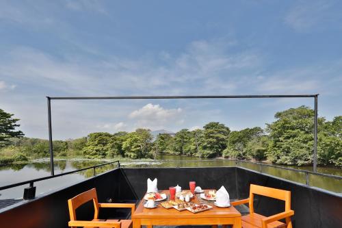 a table with food on a balcony with a view of a river at Kalundewa Retreat in Dambulla