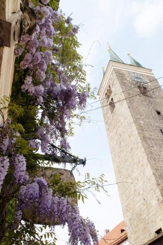 a wreath of purple flowers on a building with a clock tower at Penzion Kamenne Slunce in Telč