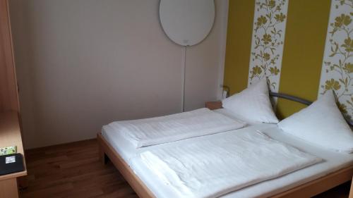 Ce lit se trouve dans un dortoir doté de draps et d'oreillers blancs. dans l'établissement Grochlitzer Pension, à Naumbourg
