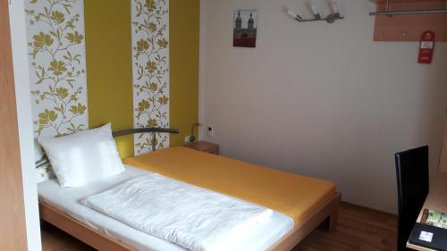 a small bedroom with a bed with yellow walls at Grochlitzer Pension in Naumburg