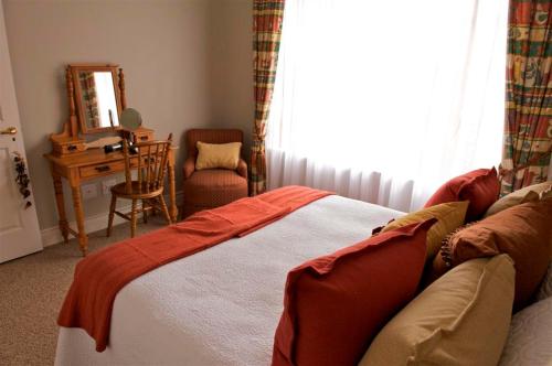 een slaapkamer met een bed, een bureau en een spiegel bij Pearl Cottage in Durban