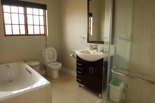 een badkamer met een bad, een wastafel en een toilet bij Pearl Cottage in Durban