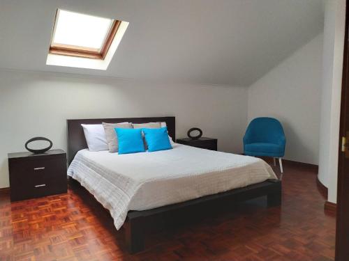 a bedroom with a bed and a blue chair at Margarida House - Stone Apartment in Ribeira Grande