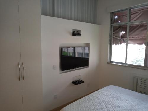 1 dormitorio con 1 cama y TV en la pared en Studio Copacabana, en Río de Janeiro
