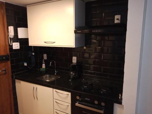 a kitchen with a sink and a black brick wall at Studio Copacabana in Rio de Janeiro