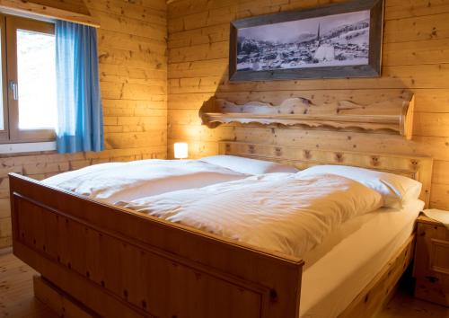 Bett in einem Zimmer mit einer Holzwand in der Unterkunft Ferienhaus Gasteg in Maria Alm am Steinernen Meer