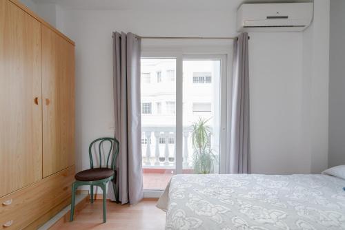 ein Schlafzimmer mit einem Bett, einem Stuhl und einem Fenster in der Unterkunft Estela Maris in Nerja