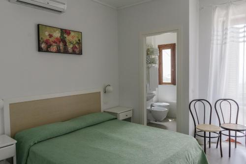 a bedroom with a green bed and a bathroom at Hotel Santa Rosalia in Marina di Camerota