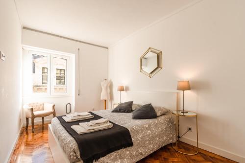 een slaapkamer met een bed, een stoel en een spiegel bij Carmo Apartments in Lissabon